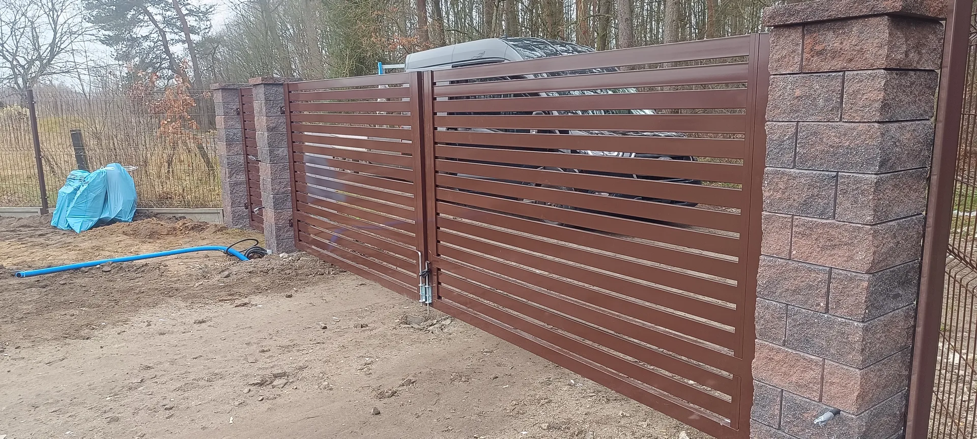 Brama wjazdowa dwuskrzydłowa metalowa z poziomymi lamelami na słupkach betonowych