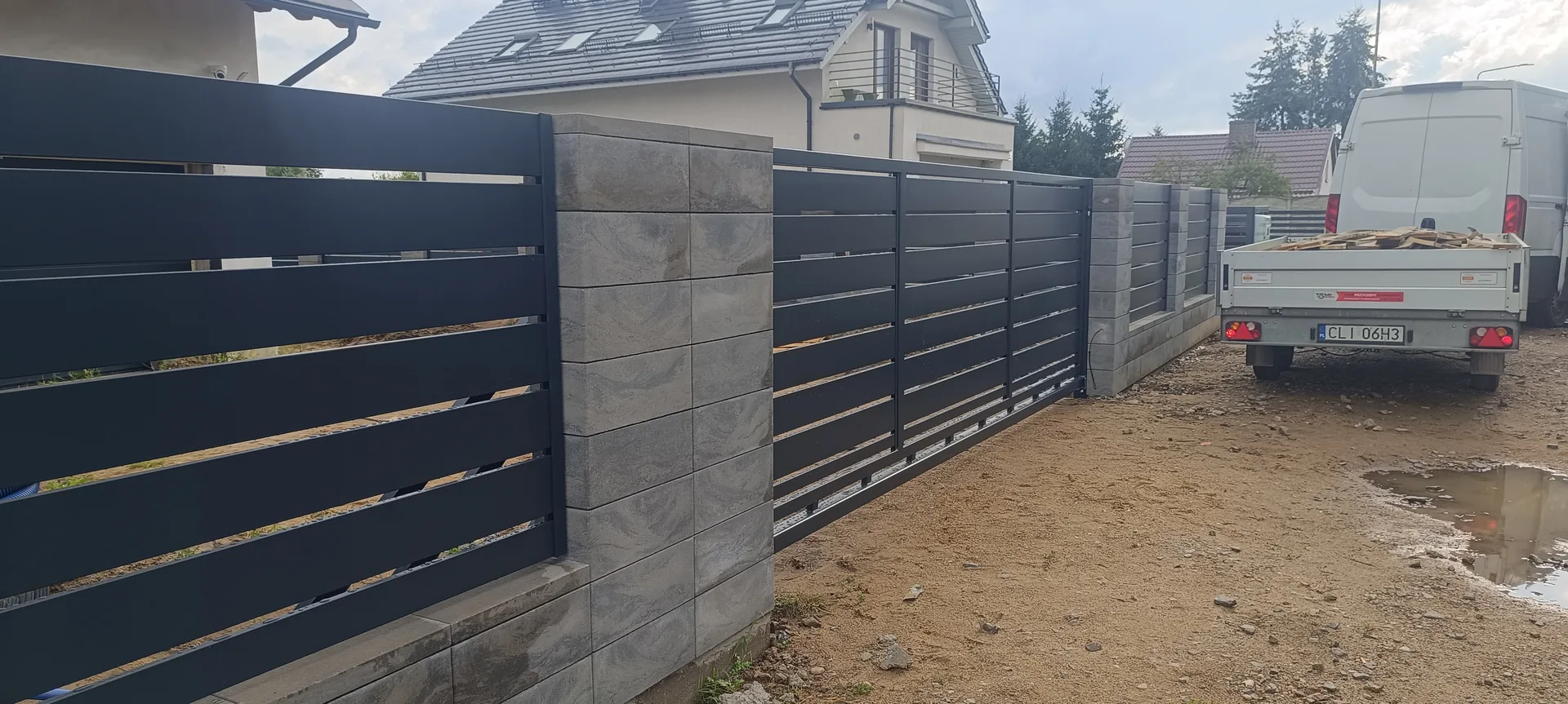 Montaż czarnych paneli metalowych na słupkach betonowych - ogrodzenia panelowe
