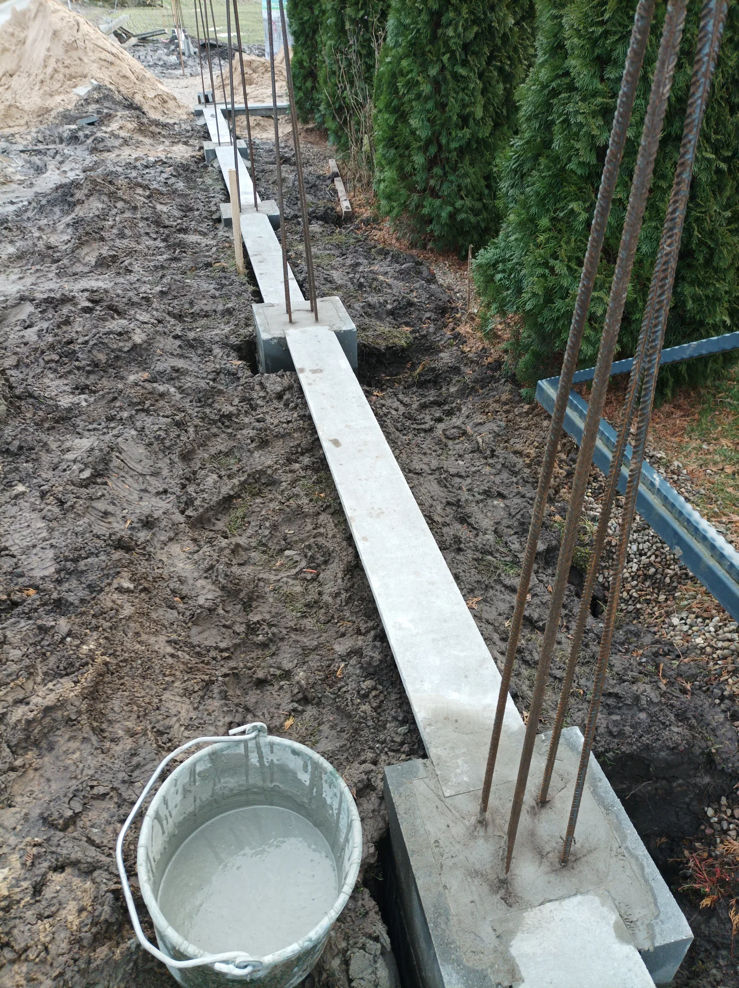 Fundament pod ogrodzenie - betonowa podstawa z metalowymi prętami zbrojeniowymi w trakcie montażu