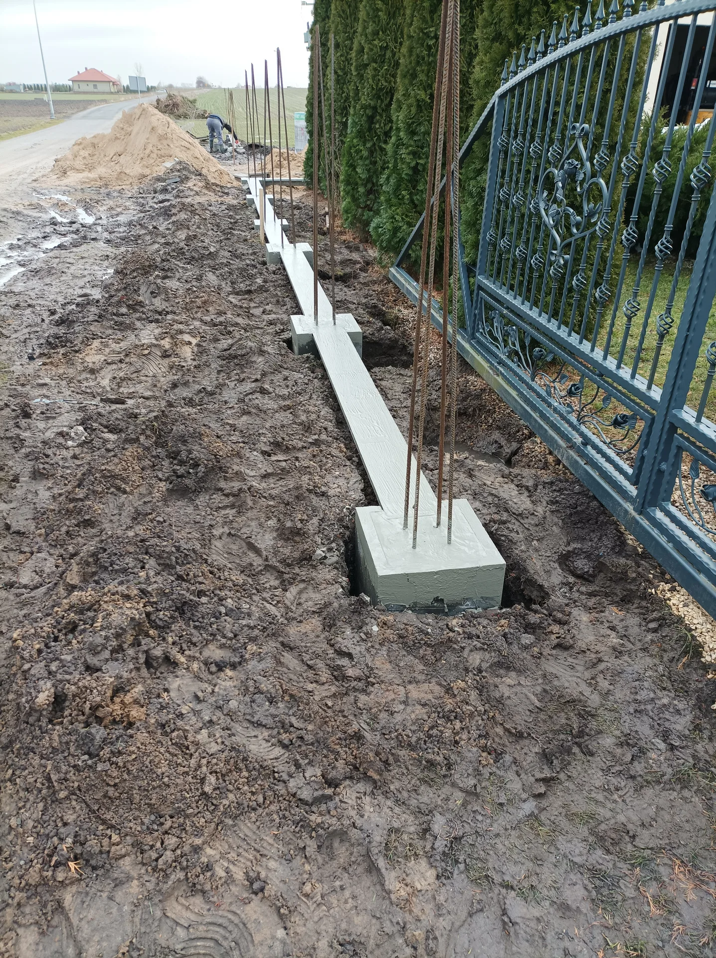 Fundament pod ogrodzenie z betonową podmurówką i metalowymi słupkami w kopie