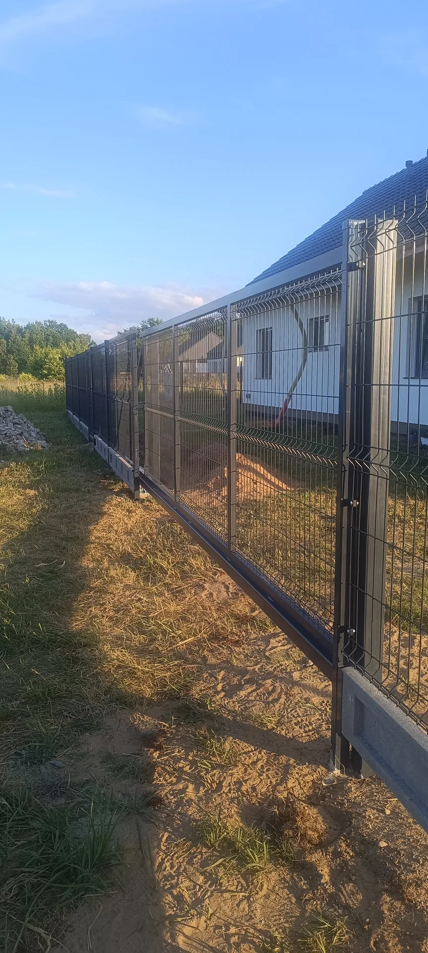 Profesjonalnie zmontowane ogrodzenie siatkowe z metalowymi słupkami i podmurówką betonową