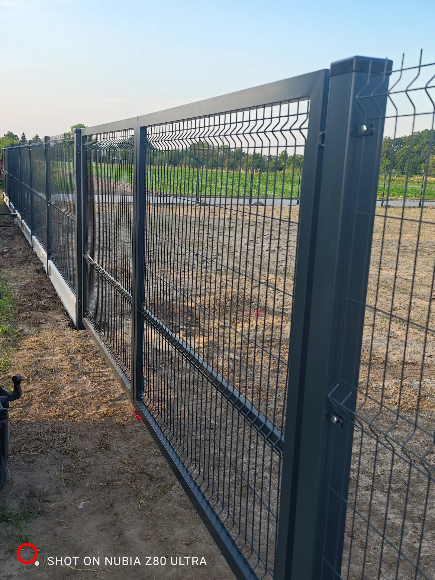 Montaż ogrodzenia siatkowego z metalowych słupków w czarnym kolorze